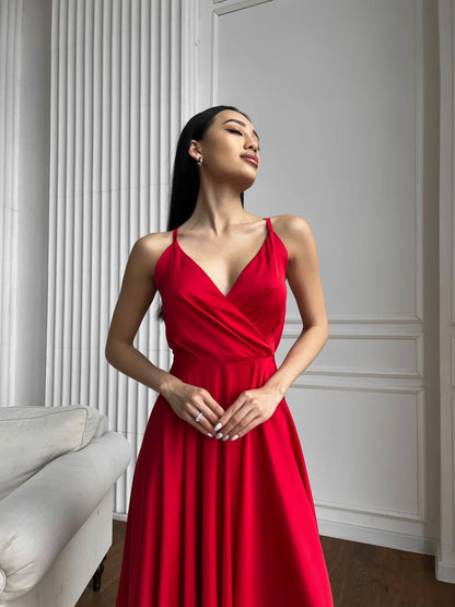Woman wearing a red dress standing against a white wall.
