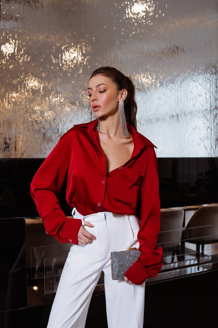 Woman wearing a red blouse and white pants with a blurred background