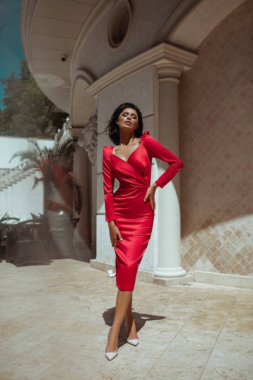 Woman in a red dress standing in front of a building with columns.