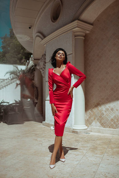 Woman in a red dress standing in front of a building with columns.