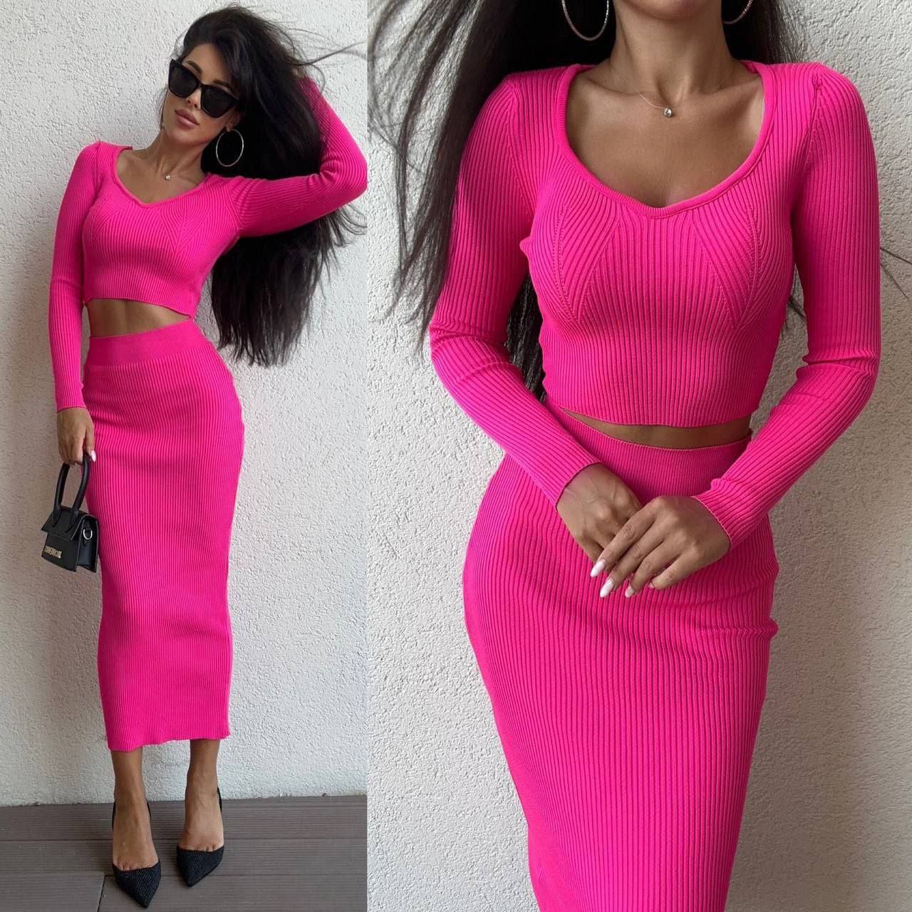Woman wearing a bright pink ribbed two-piece outfit against a plain background