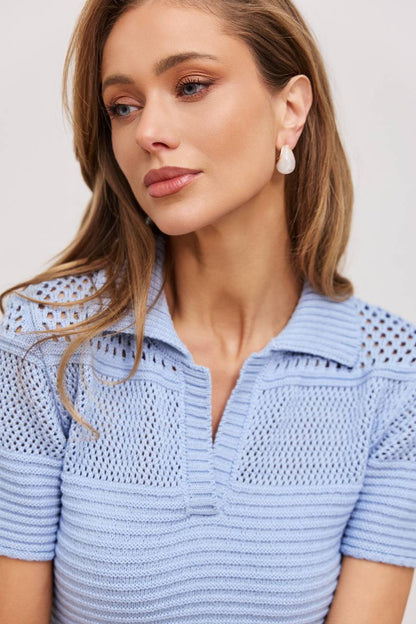 Woman wearing a light blue knitted top against a plain background
