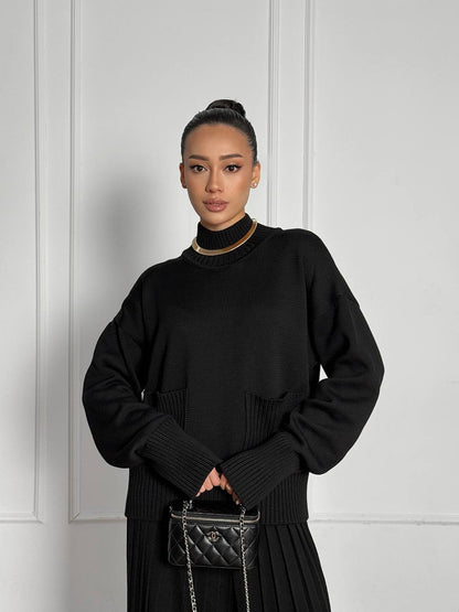 Woman wearing a black outfit with a white wall background