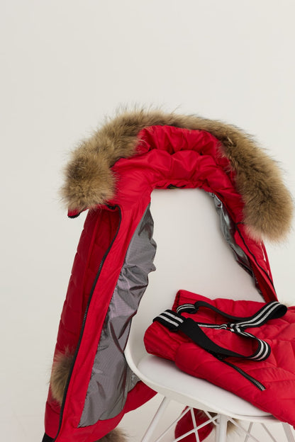 Red winter coat with fur hood on a white chair against a light background