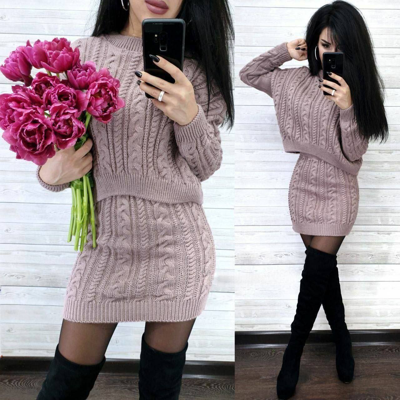 Woman in a pink cable knit dress holding pink tulips and taking a mirror selfie.