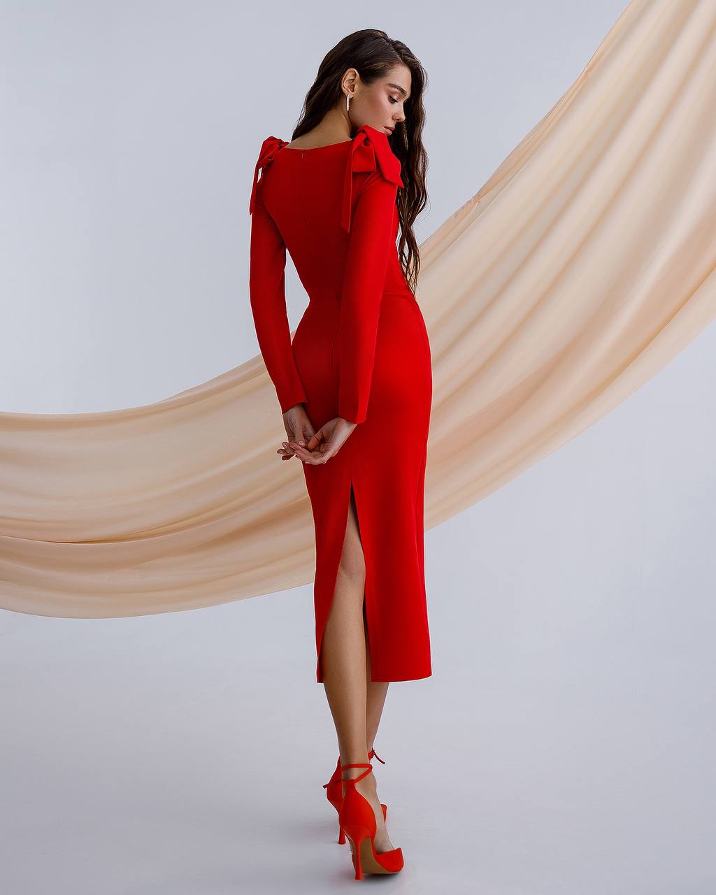 Woman wearing a red dress with a beige curtain in the background