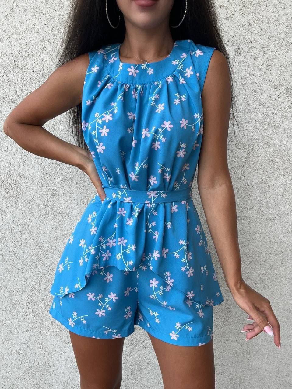 Woman wearing a blue floral romper against a gray background