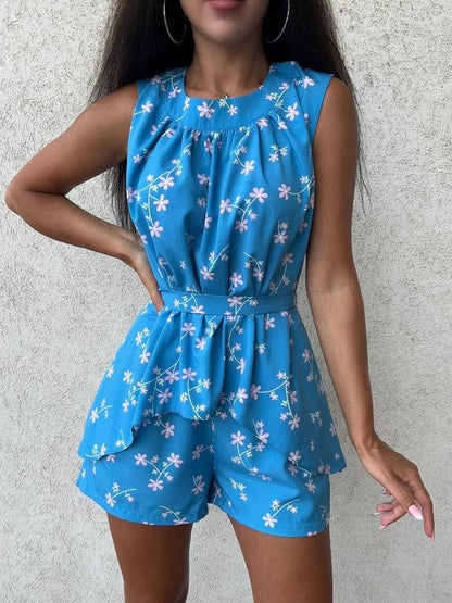 Woman wearing a blue floral romper against a gray background