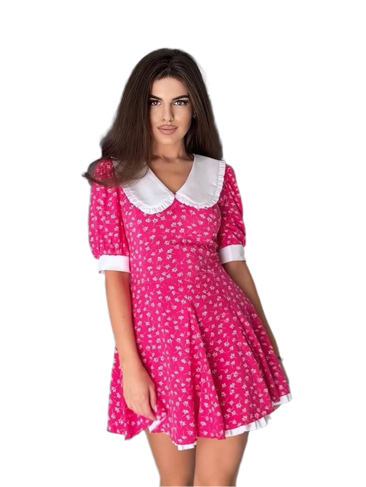 Woman wearing a pink dress with white collar and trim on a white background