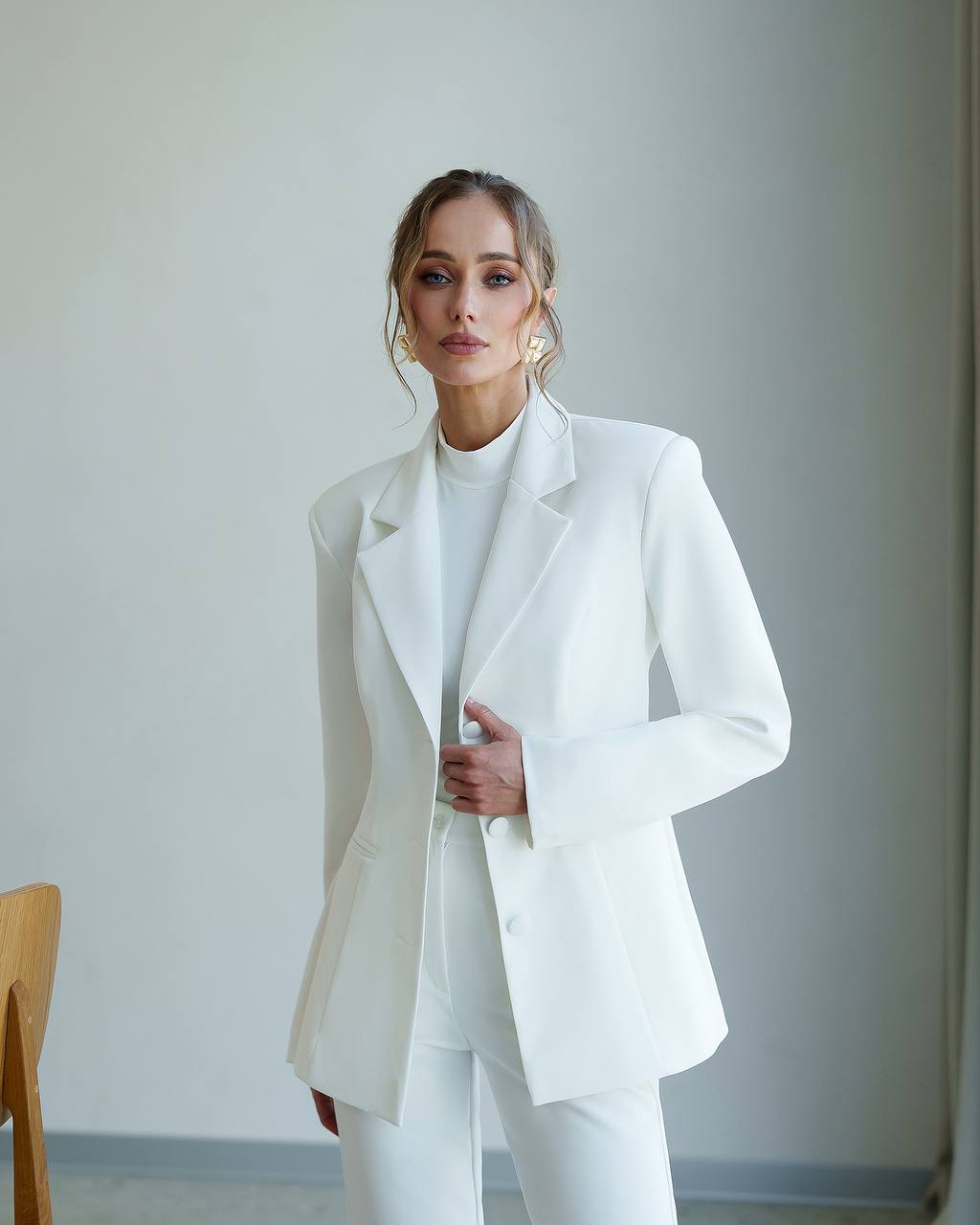 Woman wearing a white suit against a plain background