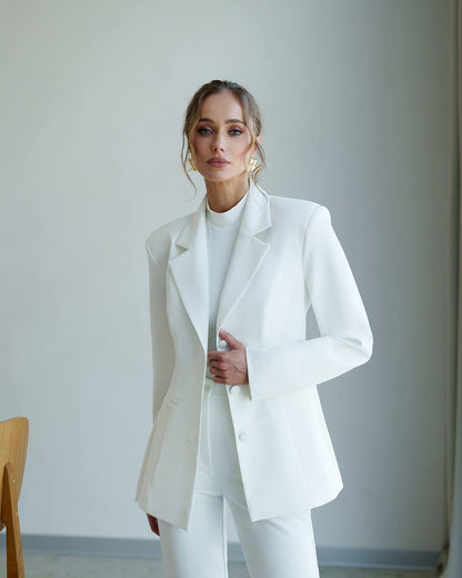Woman wearing a white suit against a plain background