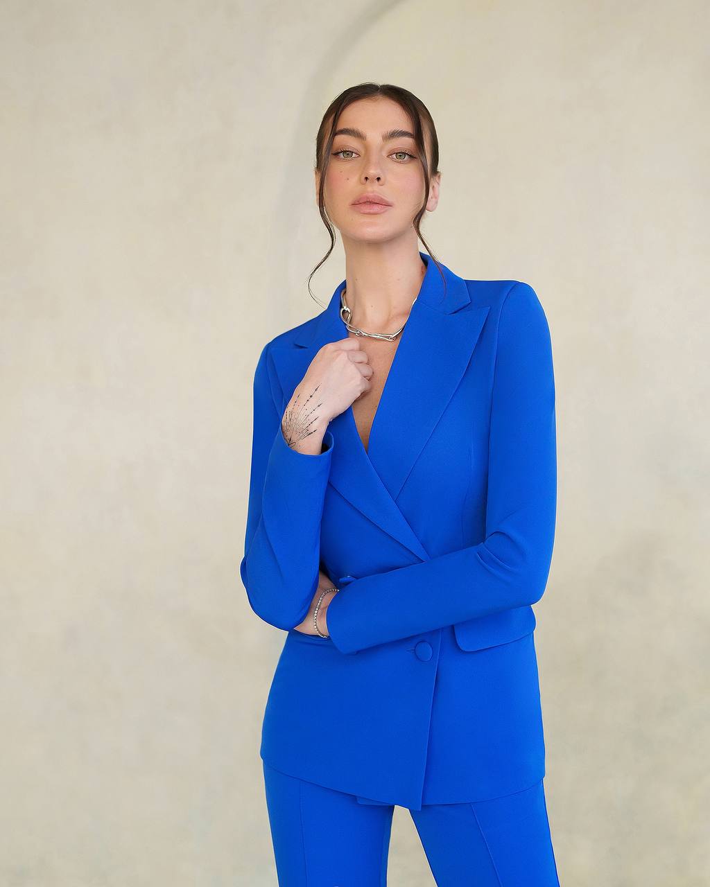Woman wearing a bright blue suit against a plain background