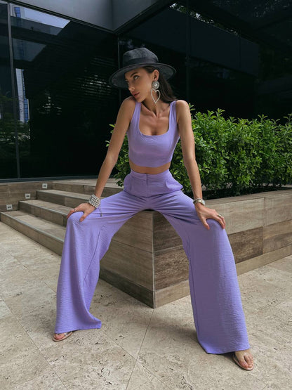 Woman in a lavender outfit posing outdoors on a stone surface.