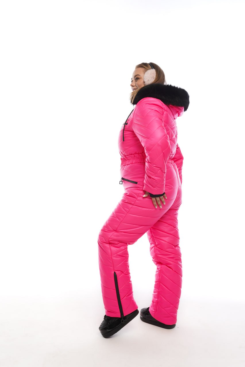 Person wearing a bright pink snowsuit with black fur trim on a white background