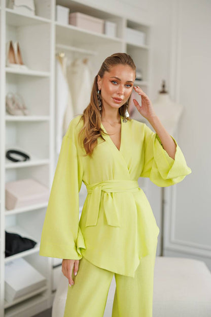 Woman wearing a bright yellow outfit in a room with shelves and a white wall.