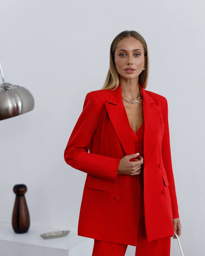 Woman wearing a red suit standing against a white background