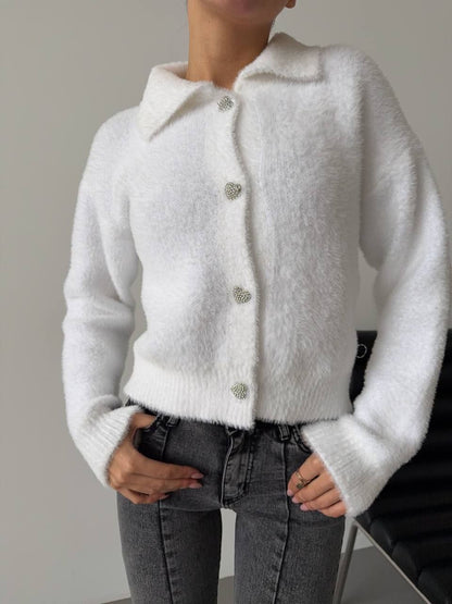 White fluffy cardigan worn by a person against a neutral background