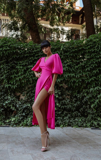 Woman in a bright pink dress standing in front of greenery