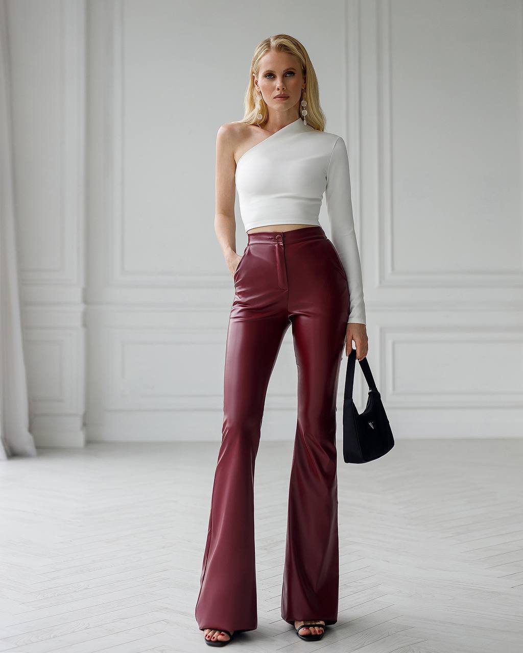 Woman wearing a white top and maroon flared pants in a minimalistic setting