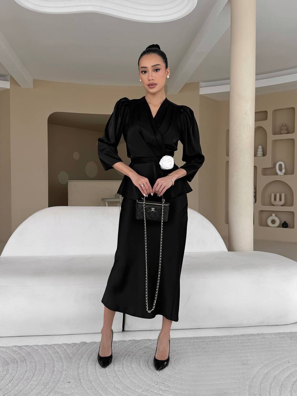 Woman in a black outfit standing in a modern interior setting