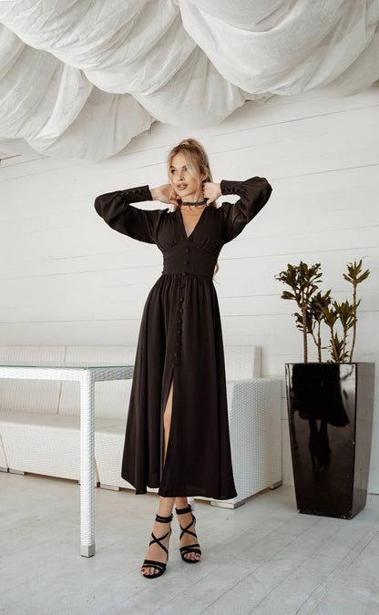 Woman in a black dress posing in a modern interior setting