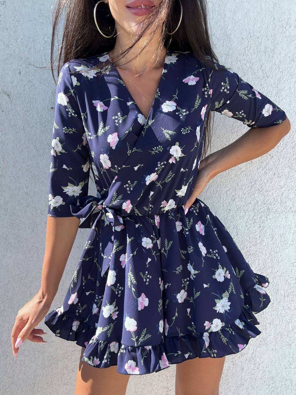 Woman wearing a navy floral dress against a light gray background