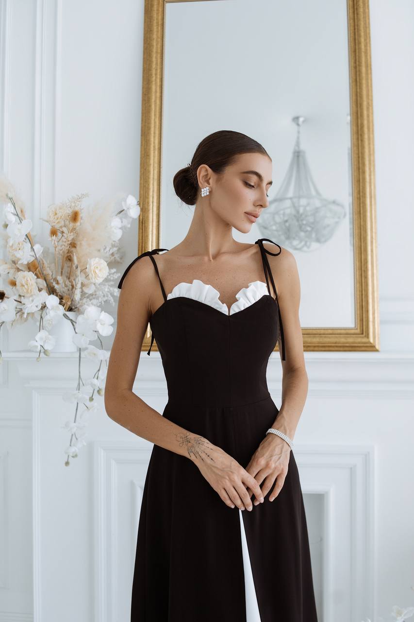 Woman wearing a black dress with white lace details in an elegant room.