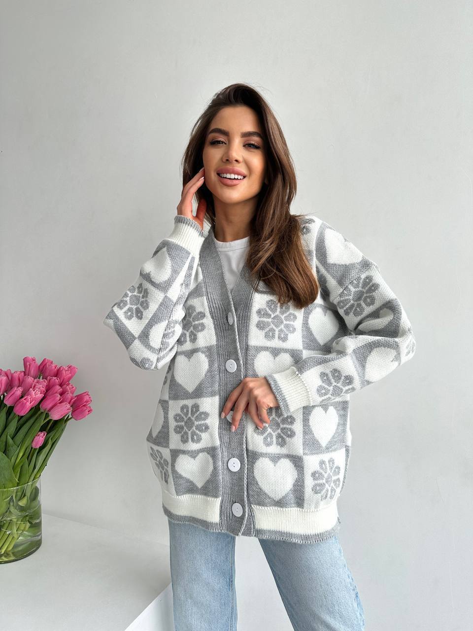 Woman wearing a gray and white patterned cardigan with pink tulips on a light background