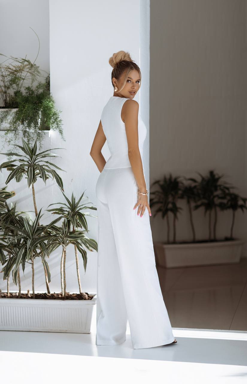 Woman in a white outfit standing in a room with plants