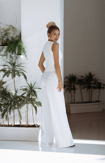 Woman in a white outfit standing in a room with plants