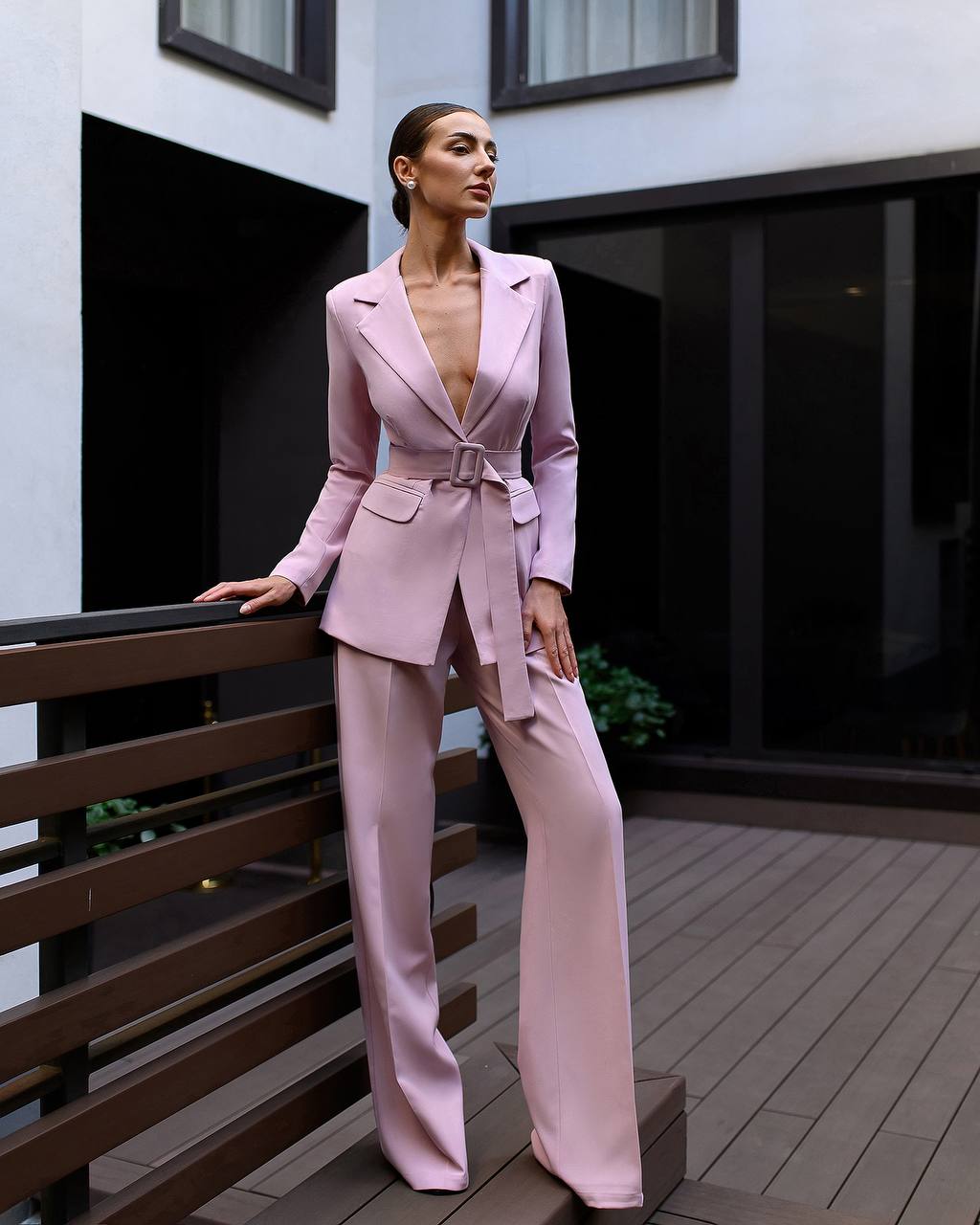 Woman in a pink suit standing on a wooden deck.
