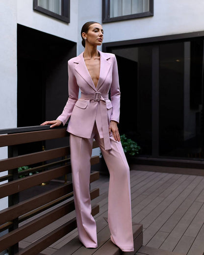 Woman in a pink suit standing on a wooden deck.