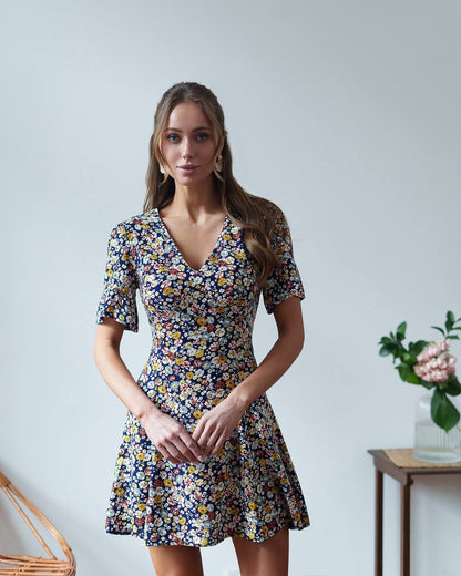 Woman wearing a floral dress against a plain background