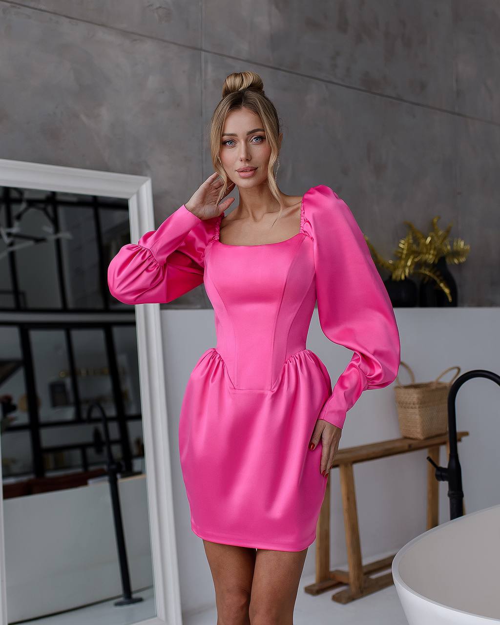 Woman wearing a bright pink dress with puffed sleeves in an indoor setting.