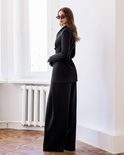 Woman wearing a black outfit standing in a room with white walls and a radiator.