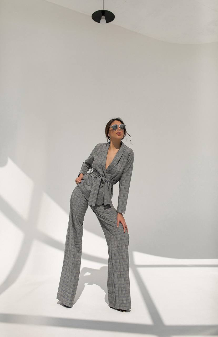 Woman wearing a gray checkered outfit in a minimal white room