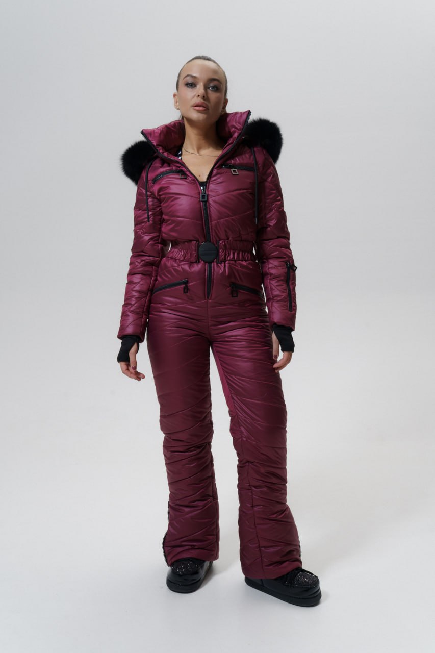 Person wearing a maroon snowsuit with black fur trim on a white background