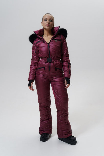 Person wearing a maroon snowsuit with black fur trim on a white background