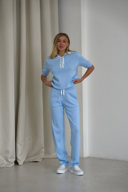 Woman wearing a light blue outfit standing against a neutral background