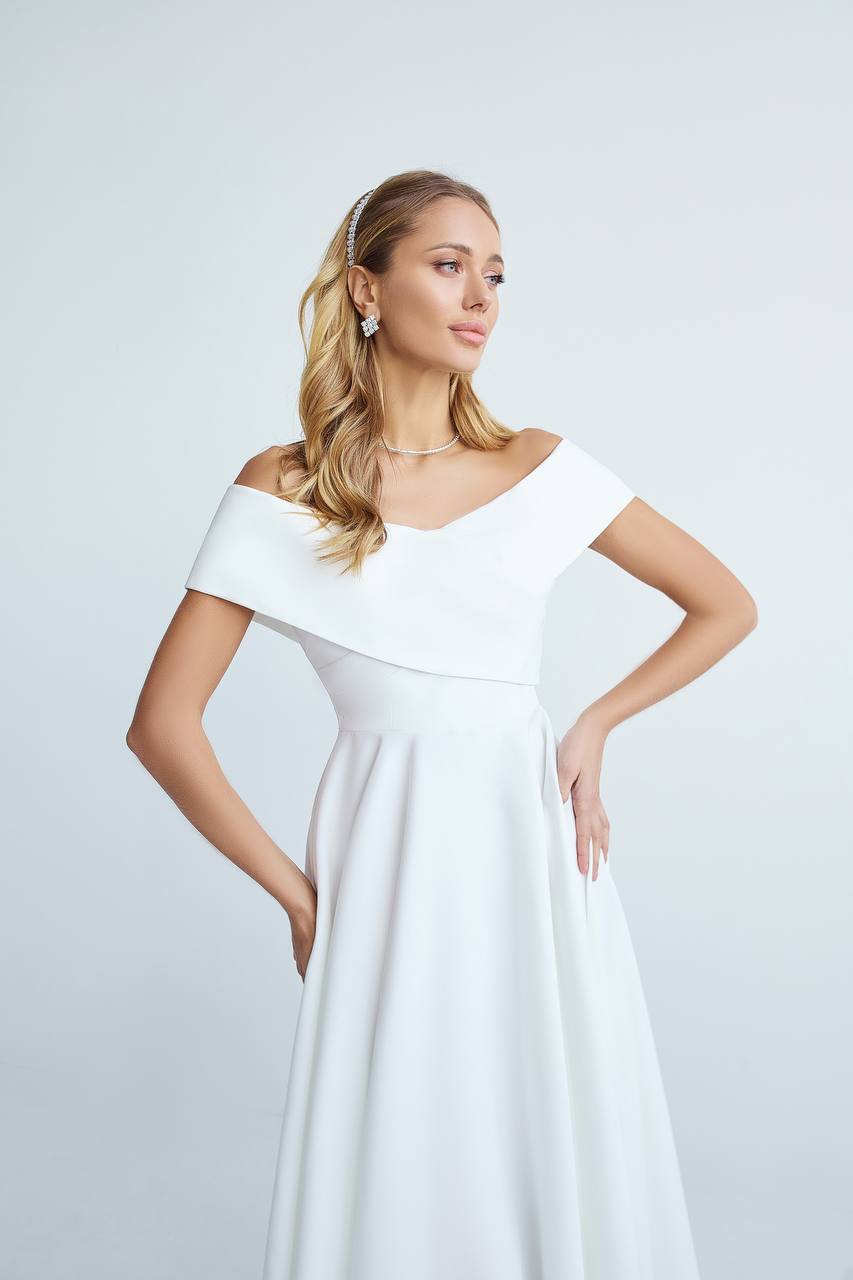 Woman wearing a white off-shoulder dress against a light gray background