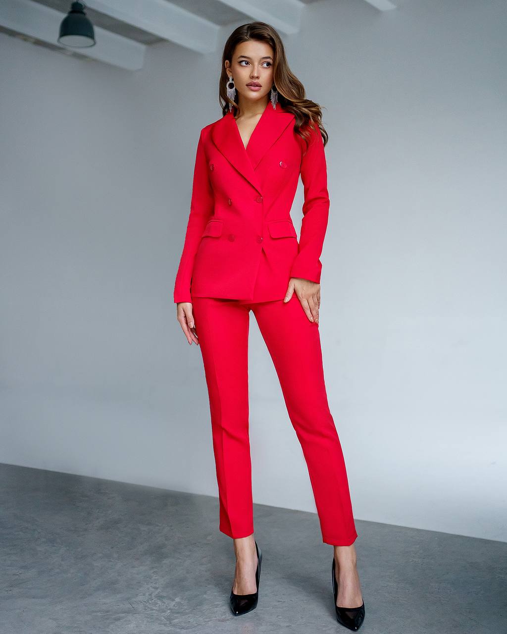 Woman wearing a red suit standing against a plain background