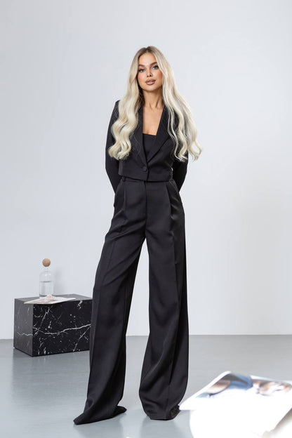 Woman in a black outfit standing against a white background