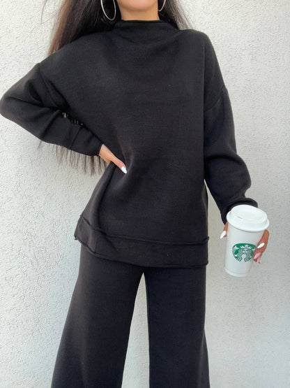 Person wearing a black outfit holding a Starbucks cup against a light background