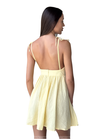 Woman wearing a light yellow dress with thin straps on a white background