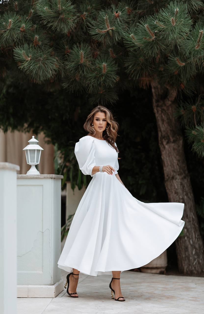 Woman in a white dress standing outdoors with trees in the background