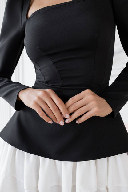 Black long-sleeve top with a fitted waist and flared skirt on a white background