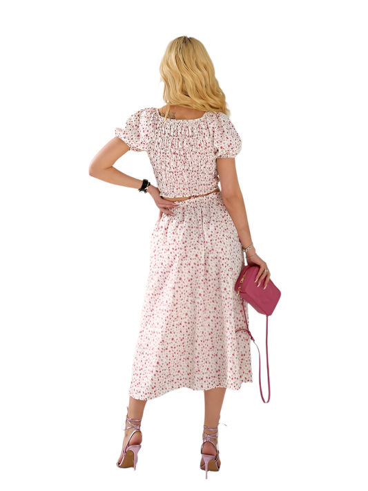 Woman wearing a pink floral dress holding a matching handbag on a white background