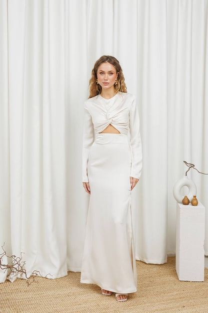 Woman in a white outfit standing in front of white curtains