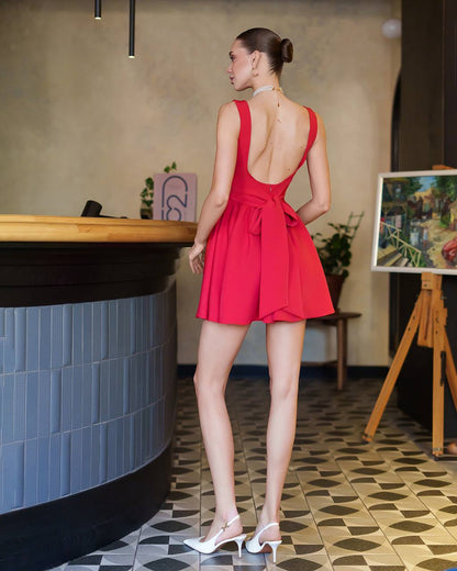 Woman in a red dress standing in an indoor setting with a counter and artwork in the background.