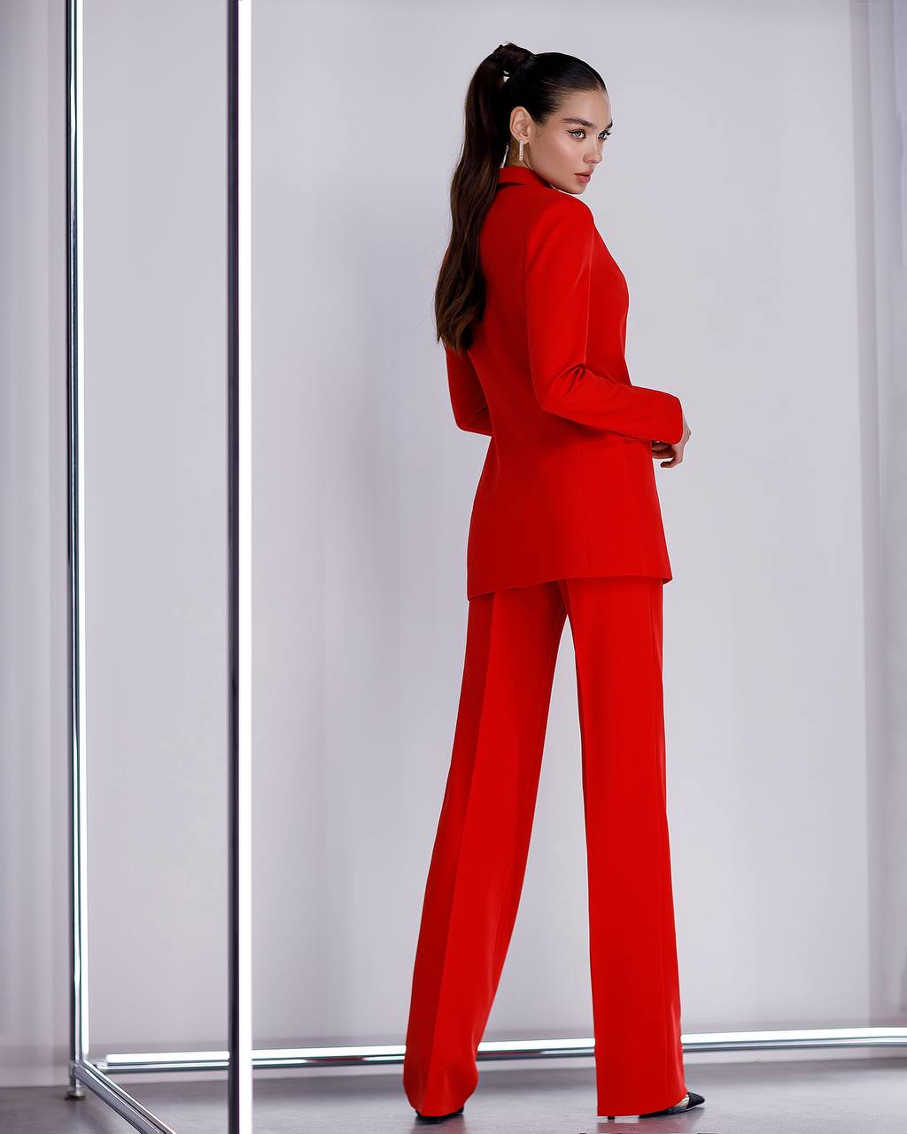 Woman wearing a red suit standing against a white background